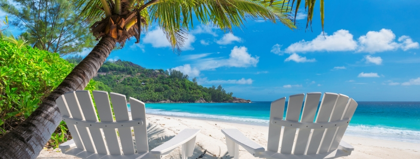 2 chaises face à la mer, avec sable blanc, palmiers et ciel bleu