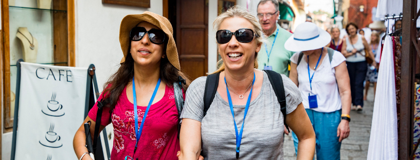 Groupe de touristes avec badges de visite découvrant une rue commerçante lors d'une excursion organisée
