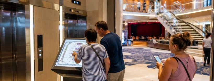 Passagers consultant le plan du navire pr&egrave;s des ascenseurs pour se rep&eacute;rer &agrave; bord
