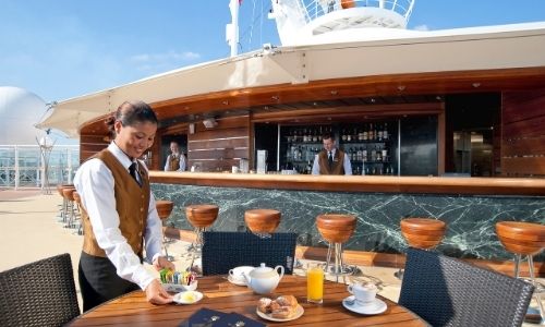  jeune femme qui sert des petites assiettes sur une table d’un bar sur le pont d’un bateau 