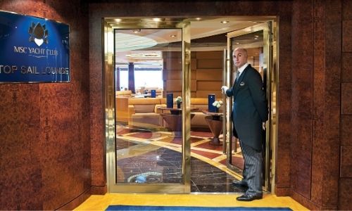 membre de l’équipe du MSC Yacht Club qui vous propose d’entrer dans le Top Sail Lounge d’un bateau MSC