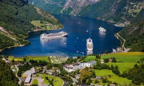 Vue sur un fjord en Norvège avec verdure, bateaux de croisière, habitations, ambiance nature