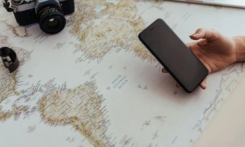 carte du monde pos&eacute;e avec un t&eacute;l&eacute;phone tenu dans la main d&rsquo;une personne