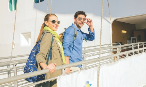 Homme et femme embarquant au sein d'un bateau de croisière avec leurs sacs à dos