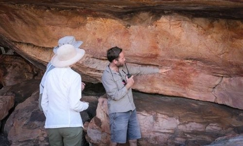 Guide présentant un lieu d’excursion à deux voyageurs
