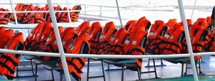 Des gilets de sauvetage oranges posés sur des chaises d'un bateau 