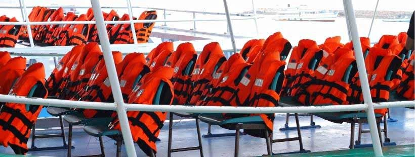 Des gilets de sauvetage oranges pos&eacute;s sur des chaises d'un bateau 