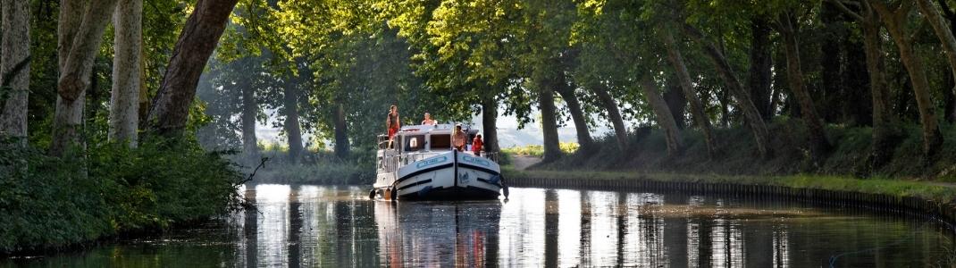 une famille à bord d'une péniche sur le canal du midi entourée d'arbres