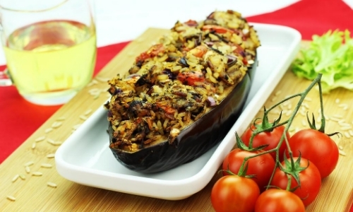 Aubergine farcie avec verre à côté et grappe de tomates