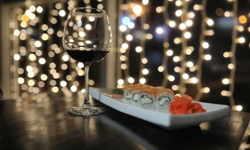 Verre de vin rouge avec une assiette de sushis &agrave; c&ocirc;t&eacute;, dans une ambiance zen