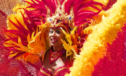 Femme déguisée pour le carnaval de Rio avec couronne et plumes rouges et jaunes