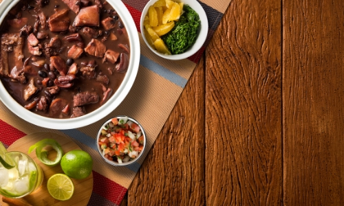 Photo du plat traditionnel national : la feijoada à base de viande de porc et haricots noirs, avec accompagnements et boisson