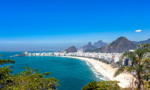 Vue sur la vaste plage de Copacabana à Rio de Janeiro au Brésil avec sable blanc, habitations tout le m-long et montagnes en arrière-plan