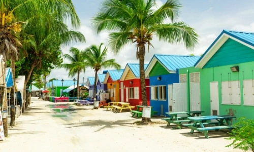 Petites maisons color&eacute;es sur le sable aux Cara&iuml;bes avec palmiers