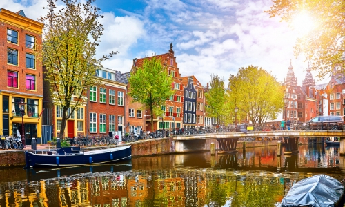 Vue sur Amsterdam avec canal, maisons colorées et arbres 