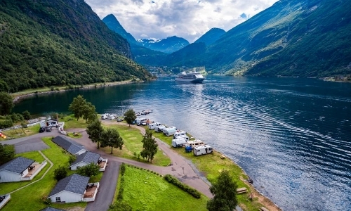 Vue depuis un fjord norvégien avec montagnes, lac, verdure, bateaux de croisière au loin