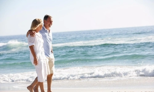 Couple marchant sur la plage, souriant