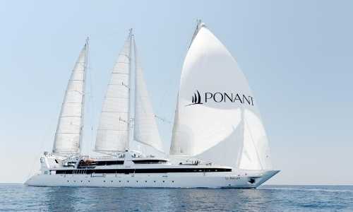 Vue sur un grand voilier de Ponant, blanc, avec inscrit PONANT en noir sur une voile