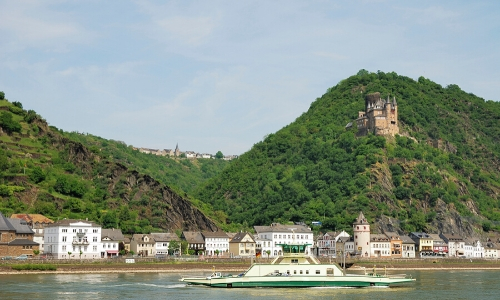 Bateau naviguant tranquillement sur le Rhin, avec petites habitations aux alentours et verdure