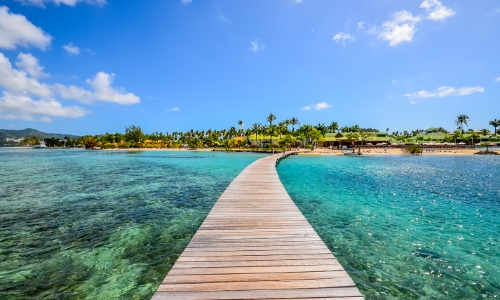 Vue sur un ponton donnant sur la plage en Martinique avec eau turquoise