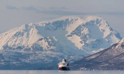 bateau de croisière sur l'eau au beau milieu d’immenses montagnes enneigées