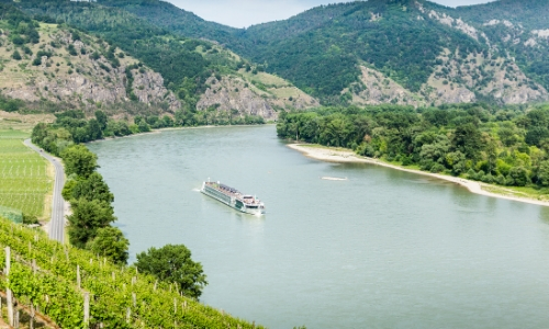 Vue en hauteur sur le fleuve du Danube, avec bateau naviguant, entouré de verdure
