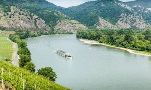 Vue en hauteur sur le fleuve du Danube, avec bateau naviguant, entouré de verdure