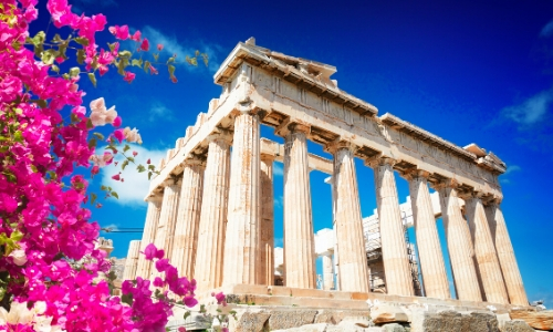 Le Parthénon et ses colonnes, fleurs roses sur le côté de la photo, ciel bleu