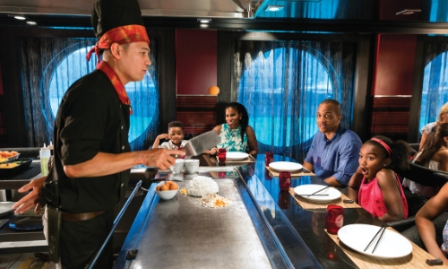 Clients autour d'une table dans un restaurant avec chez au centre qui cuisine devant eux