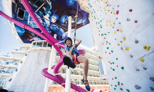 Fille qui s'amuse sur un mur d'escalade, accrochée 