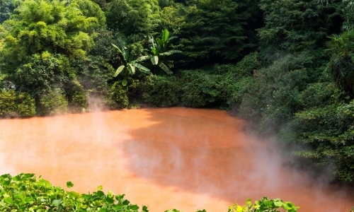 Source naturelle d'eau chaude couleur orangée en plein milieu de la nature