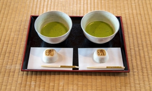 Deux bols de thé vert matcha accompagnés d'une petite friandise