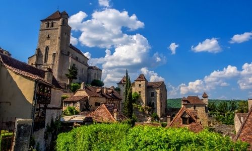 village du Lot, vue sur de grands bâtiments de ce village, le ciel est bleu et le soleil est au rendez-vou