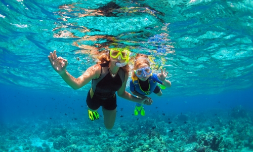 Une femme et son enfant sous l'eau pratiquant le snorkelling 