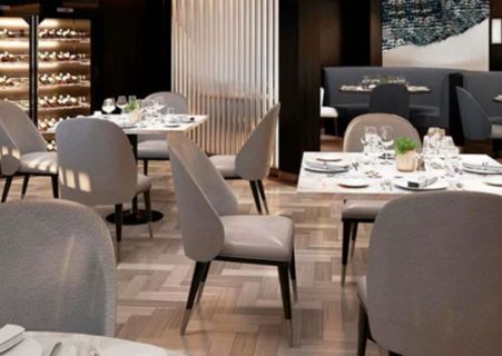 intérieur d’un restaurant avec les tables dressées dans une ambiance taupe, neutre et épurée prêt à accueillir les convives. 