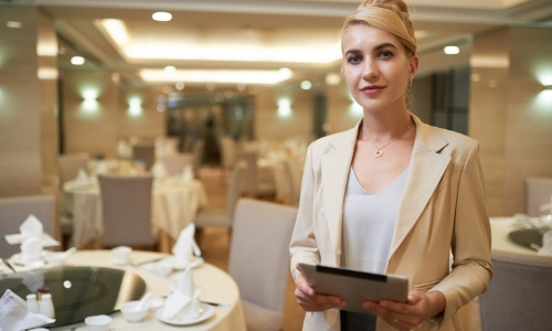 Portrait d'une wedding planner, sur fond de tables préparées pour une soirée/cérémonie