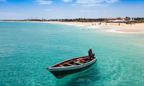 Eaux limpides du Cap-Vert, avec barque sur l'eau et plage de sable blanc