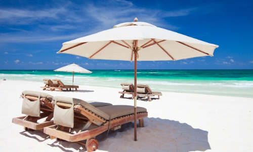 Transats et parasols blancs sur une plage de sable blanc au Caraïbes