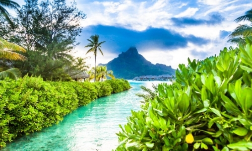 Vue sur un paysage tropical avec verdure entourant un lagon bleu turquoise, montagne en fond