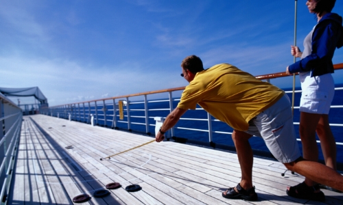 Couple jouant au shuffleboard sur pont d'un bateau 