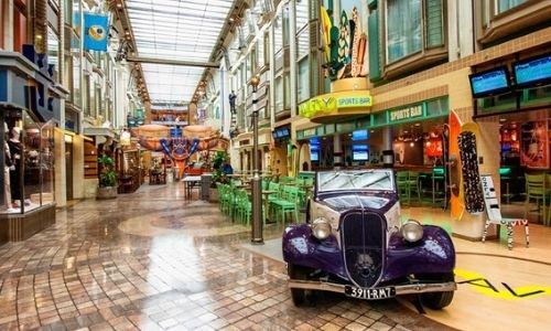 intérieur d’un bateau avec une vieille voiture au premier plan et l’allée d’une galerie marchande