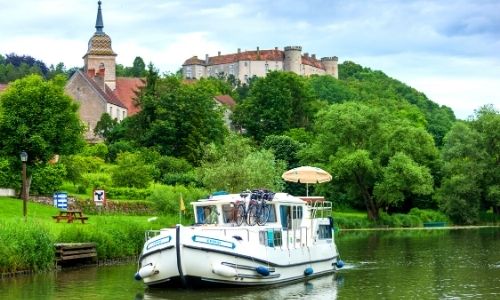 péniche sur l'eau, entourée de villages en bordure du canal