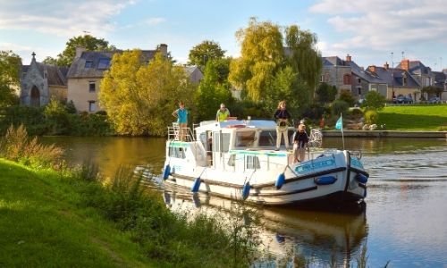péniche qui navigue sur un canal avec 4 personnes à son bord