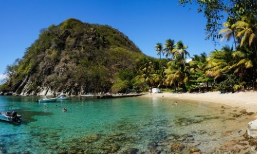 Bord de mer, ambiance naturelle avec plage de sable blanc, verdure, eau turquoise