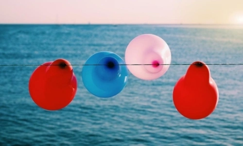 Ballons couleurs bleu rouge et blanc suspendus à un fil face à la mer
