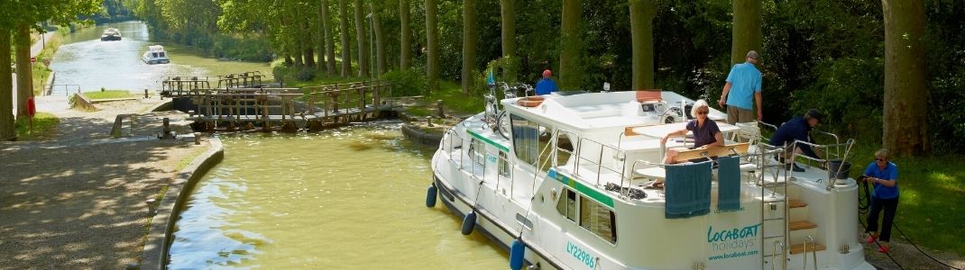 Un bateau de location sans permis sur le canal du midi qui approche une écluse