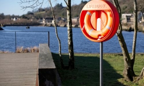  Bord d’une rivière avec une bouée de sécurité orange à droite d’un ponton en bois