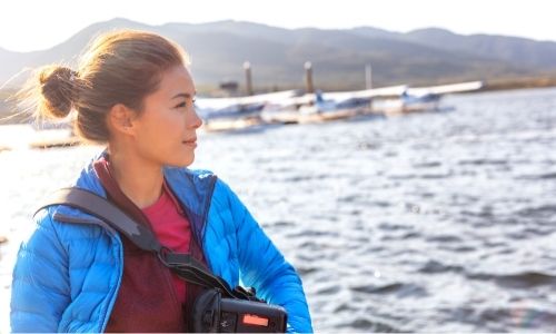 Jeune femme qui regarde l'horizon sur un bateau de croisière, équipée pour une excursion