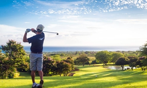 Joueur de golf, de dos, sur son parcours, face à la mer