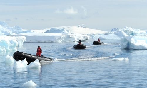 experts des zones polaires dans des petits bateaux sur la mer, entourés de blocs de glace